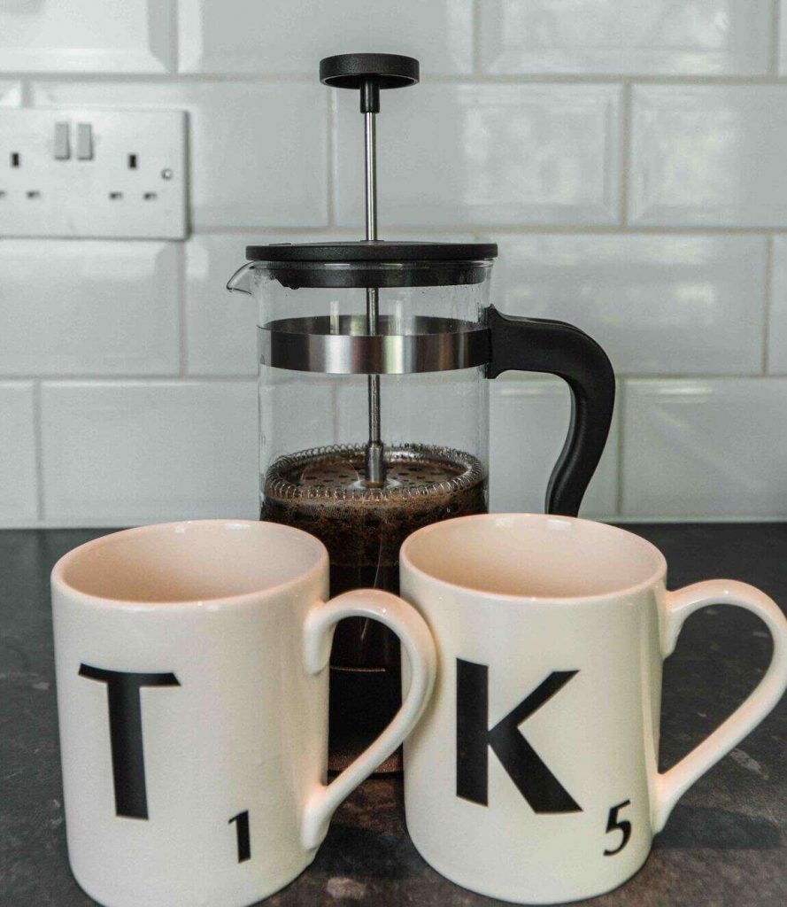 French press with coffee mugs in front