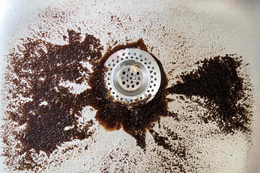 Coffee grounds trying to drain down a sink.