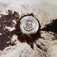 Coffee grounds trying to drain down a sink.